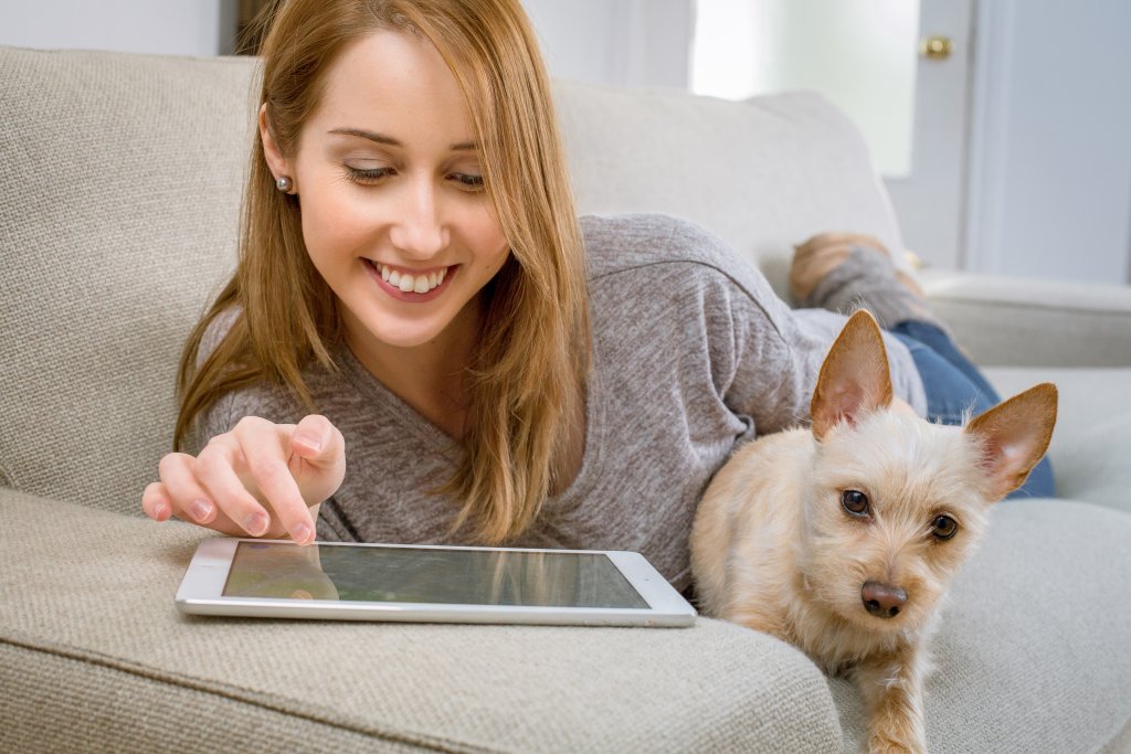 Ragazza con tablet e cane sul divano