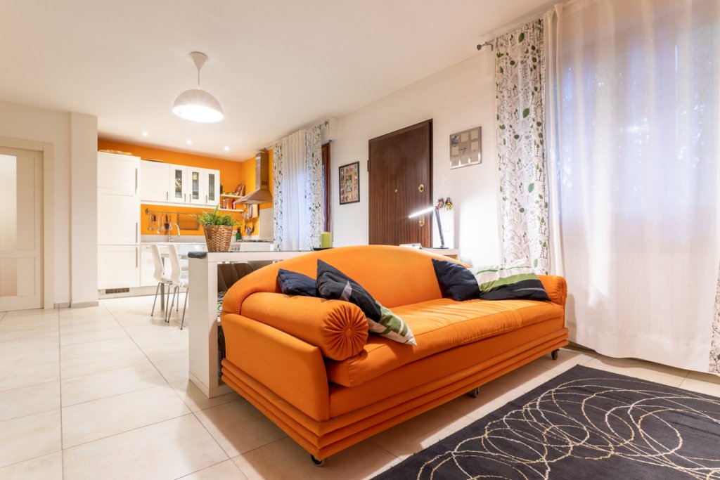 Soggiorno open space con divano arancione Ristrutturazione divisione appartamento a Campi Bisenzio Firenze