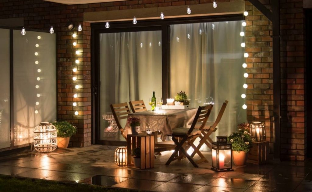 Apri la finestra alla primavera: i consigli per arredare il balcone | Facile Ristrutturare terrazza con tavolo e sedie. Luci a cascata, lanterne e vasi con fiori