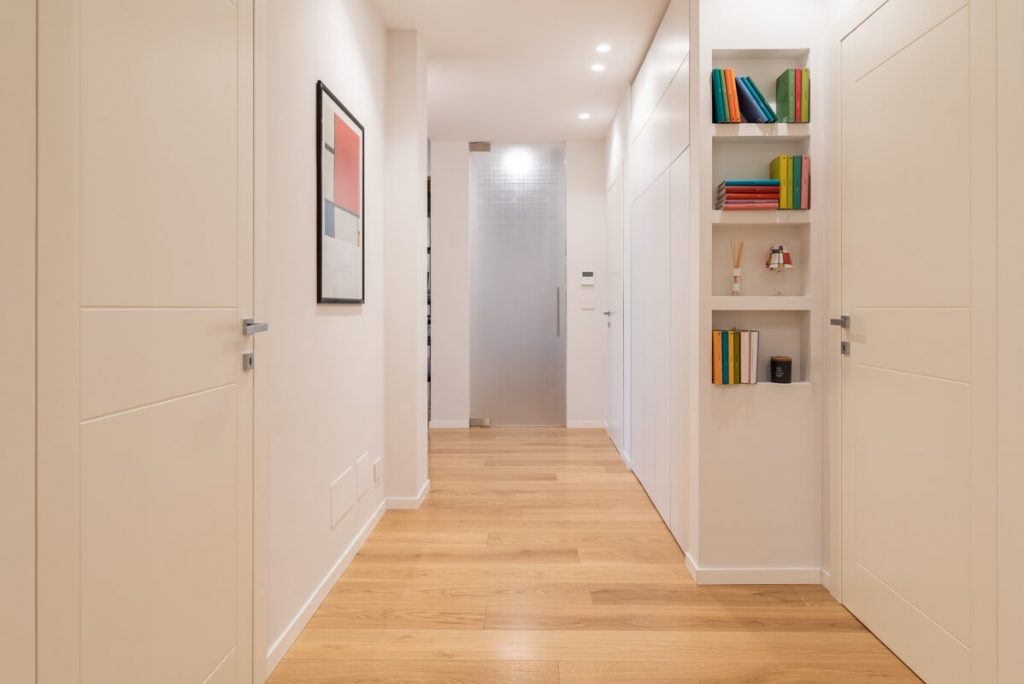Corridoio con libreria a muro ikea e quadri colorati sulle pareti