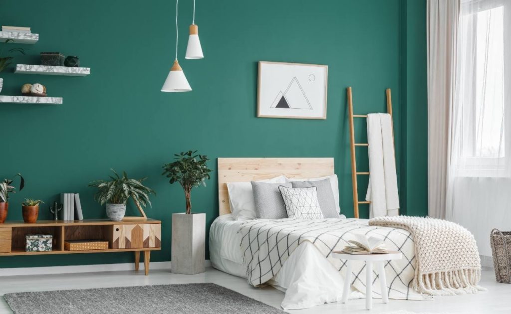 5 errori da evitare nell'arredamento secondo Paola Marella | Facile Ristrutturare Camera da letto matrimoniale con paretei verde, mensole di marmo e lampadari a sospensione. Scala di legno appoggiata alla parete e piante verdi.