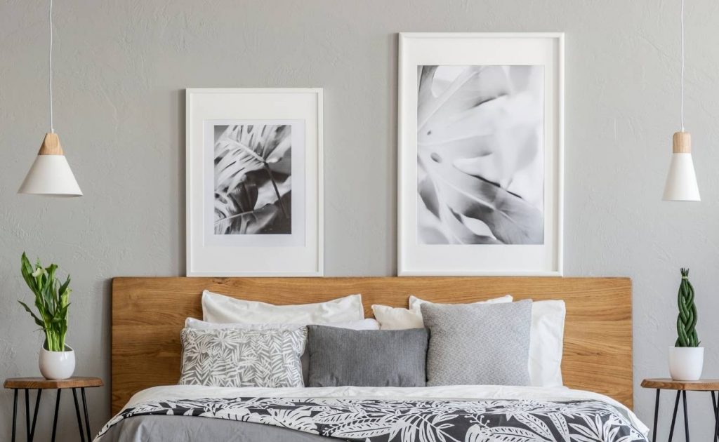 5 errori da evitare nell'arredamento secondo Paola Marella | Facile Ristrutturare camera da letto matrimoniale con testa in legno, lampadari a sospensione e quadri con immagini bianche e nere. Comodini in legno con piante verdi.