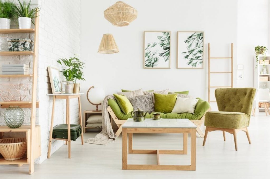 Stile Jungle per la casa vacanze di Paola Marella | Facile Ristrutturare Soggiorno stile jungle con divano e poltrona verde. Libreria con piante e quadri con piante verdi.