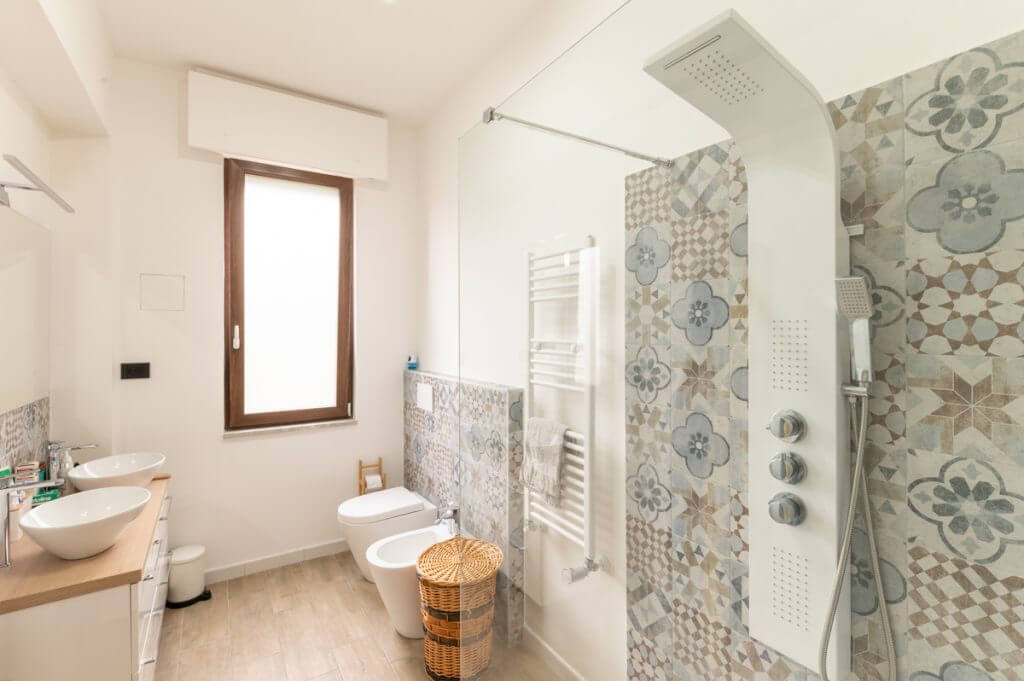 Bagno moderno con doppio lavabo d'appoggio e rivestimenti in cementine.