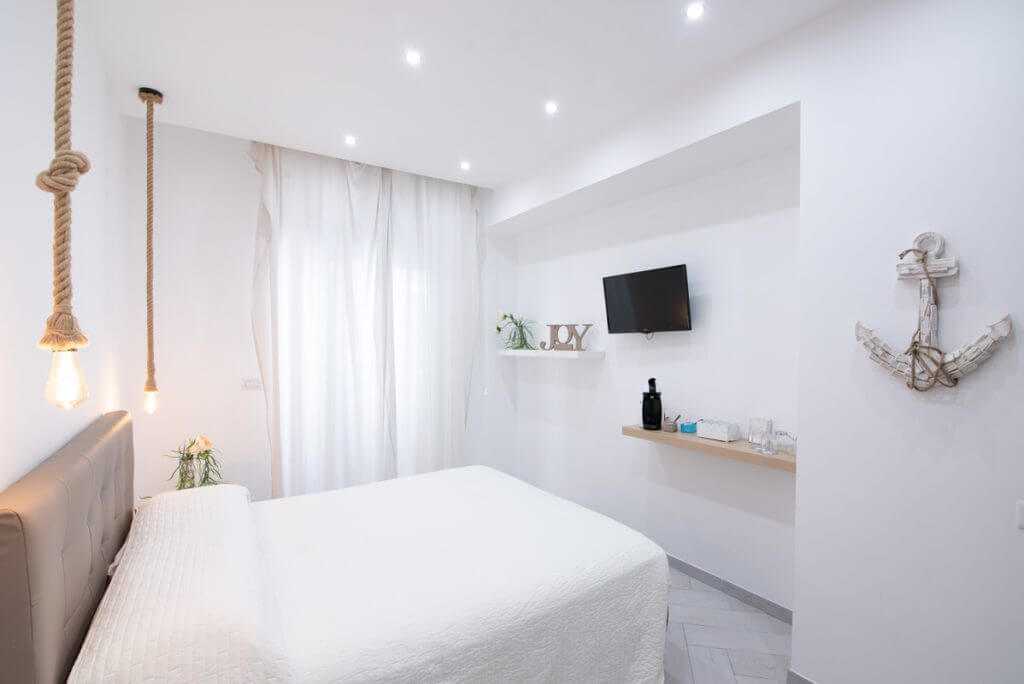 Camera matrimoniale per bed and breakfast con mensole e tv sulla parete.