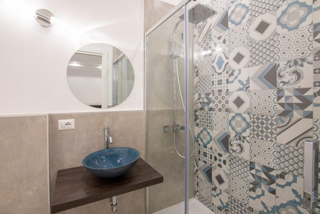 Bagno moderno con specchio rotondo e lavabo d'appoggio blu.