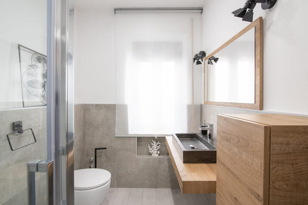 bagno moderno con sanitari bianchi e lavabo nero con mobile in legno.