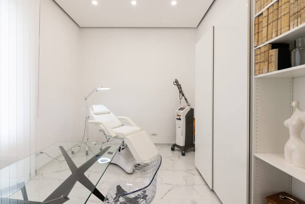 studio medico con lettino e scrivania in vetro.