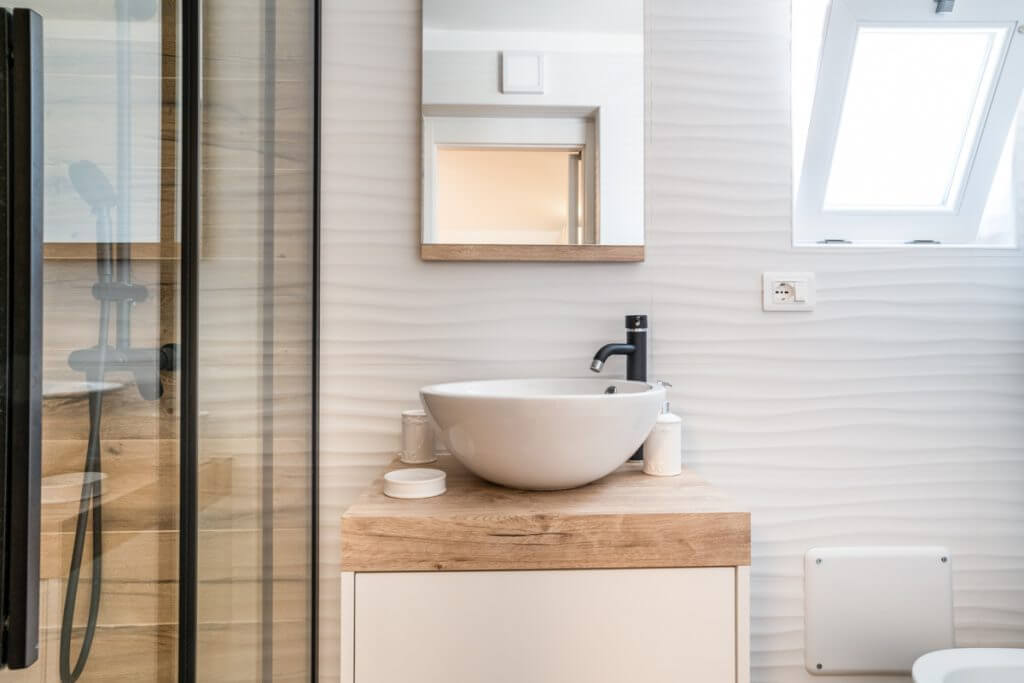 bagno moderno con lavabo rotondo d'appoggio su mobile in legno.
