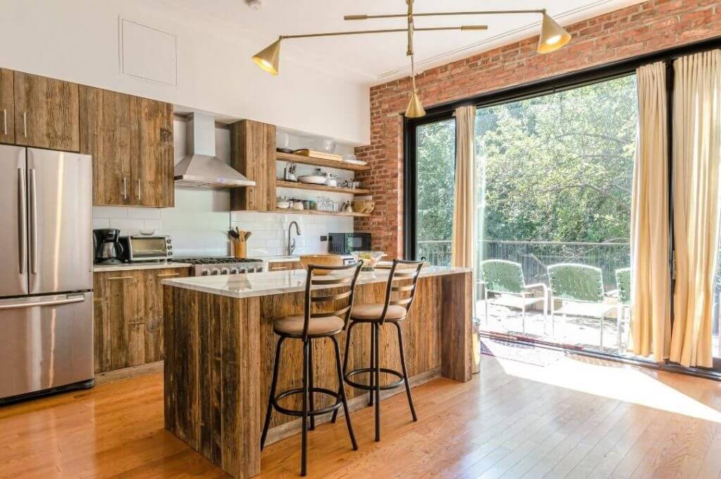 idee per ristrutturare casa di campagna: cucina con isola e parete con mattoncini.