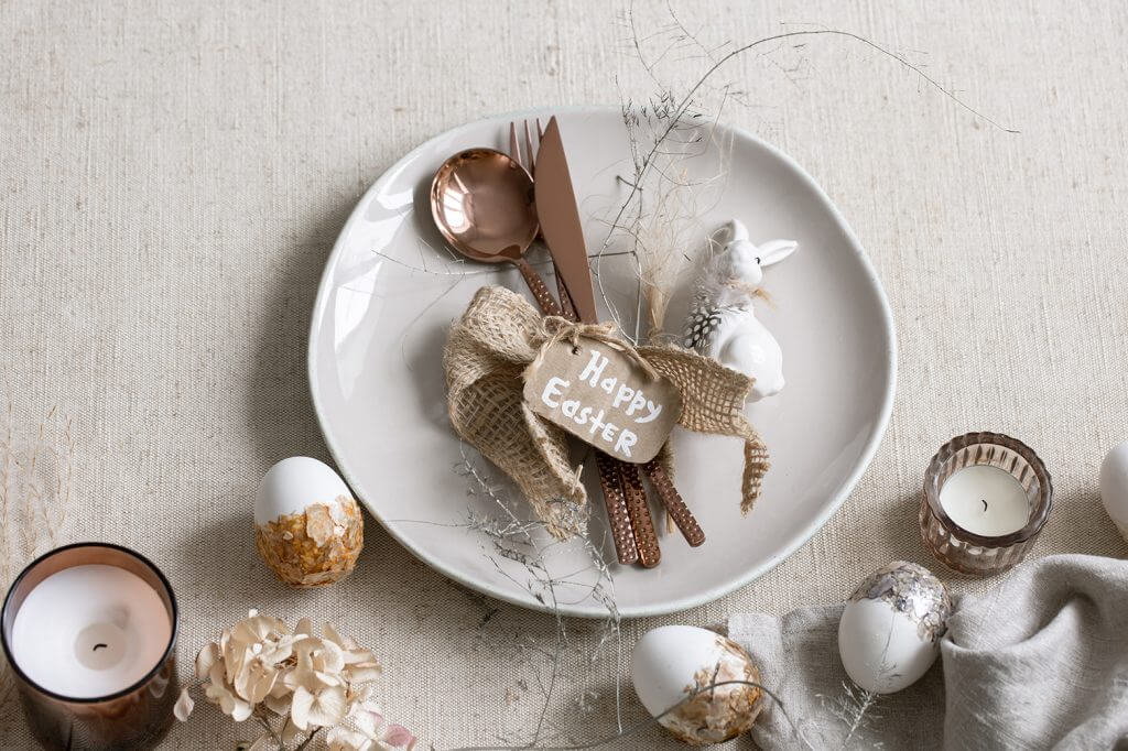Addobbo per piatto con uova decorate e candele sul tavolo