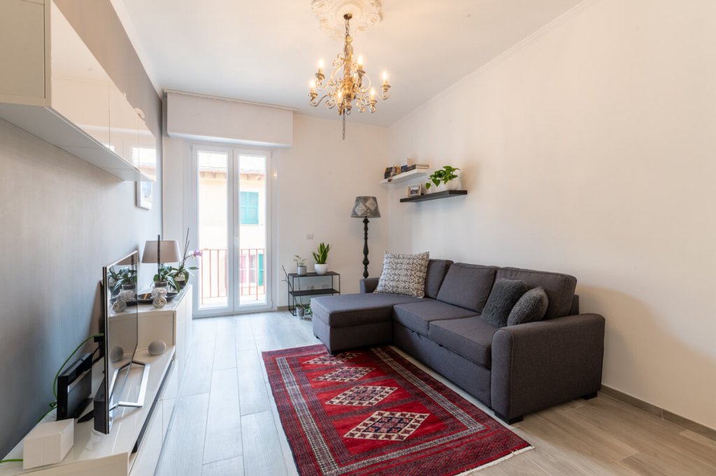 Soggiorno con parquet chiaro e tappeto rosso