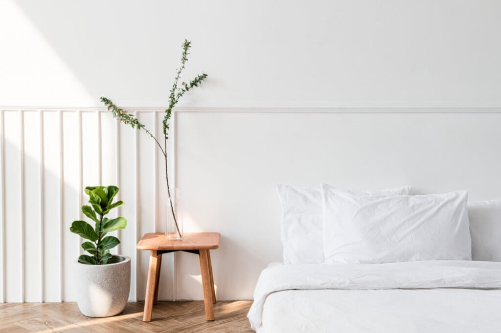 Ad ogni stanza la sua pianta! Come arredare casa con le piante da interni | Facile Ristrutturare Letto con lenzuola e cuscini bianchi e sgabello laterale in legno