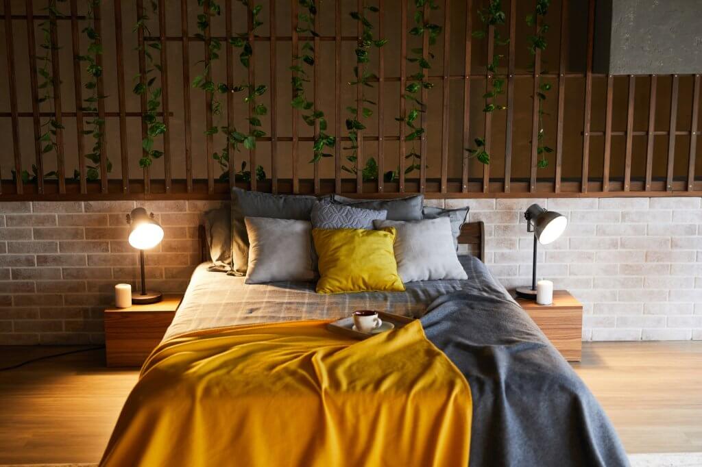 Ad ogni stanza la sua pianta! Come arredare casa con le piante da interni | Facile Ristrutturare Camera da letto con cuscini colorati, testata in legno e lampade laterali