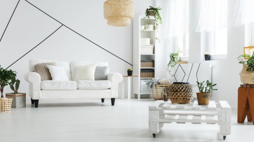 Soggiorno con divano e arredamento bianco, con tavolo in pallet e libreria