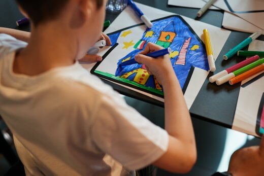 Bambino che disegna con colori su un foglio