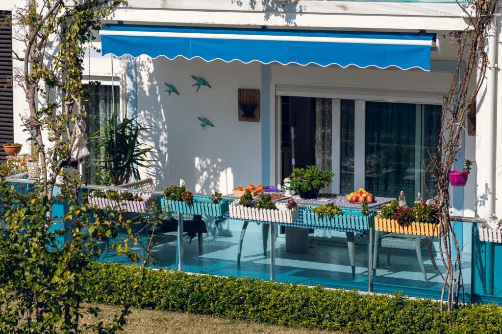 Bonus tende da sole 2022, detrazione del 50% | Facile Ristrutturare Balcone con fiori in vaso, finestra laterale bianco, tende da sole blu
