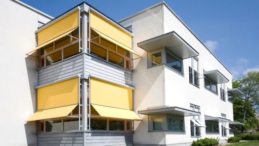 casa con tende sole gialle e alberi laterali