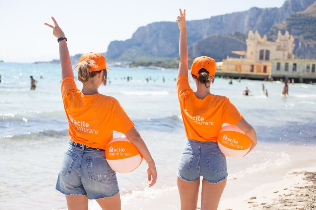Hostess con maglia e palla di Facile Ristrutturare in spiaggia con gadget