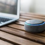 Dispositivo Alexa con tavolo in legno e computer laterale