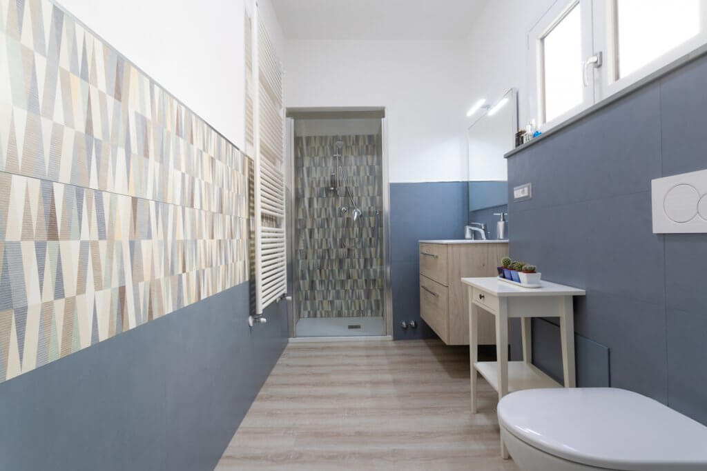 Ristrutturazione casa a Piombino, bagno con pareti blu e doccia walkin