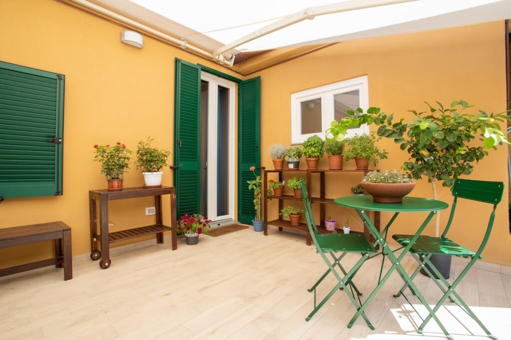 Ristrutturazione casa a Piombino, veranda balcone con imposte verdi, tavolino, sedie e pieante
