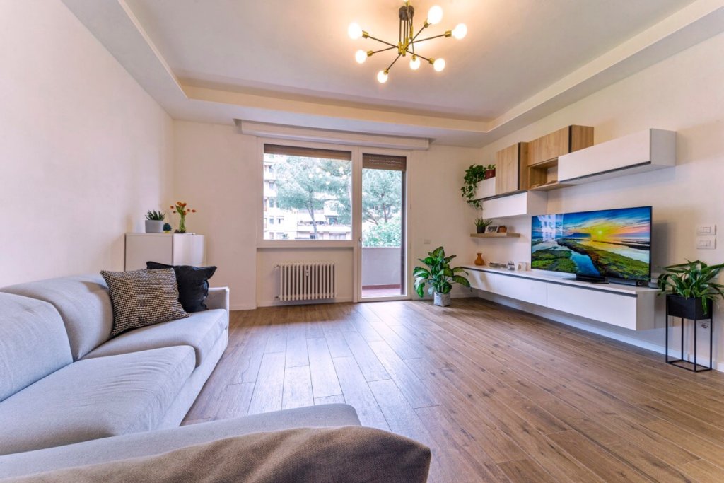 Soggiorno con pavimento in legno e arredamento bianco
