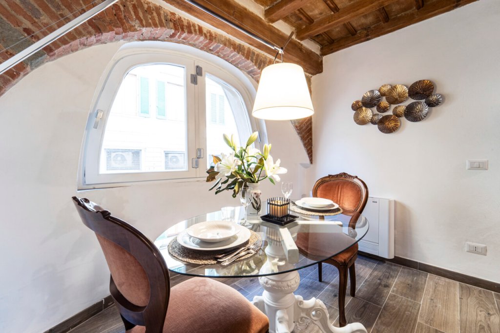 Tavolo da pranzo in vetro muro in mattoncini rossi pavimento in gres porcellanato effetto legno