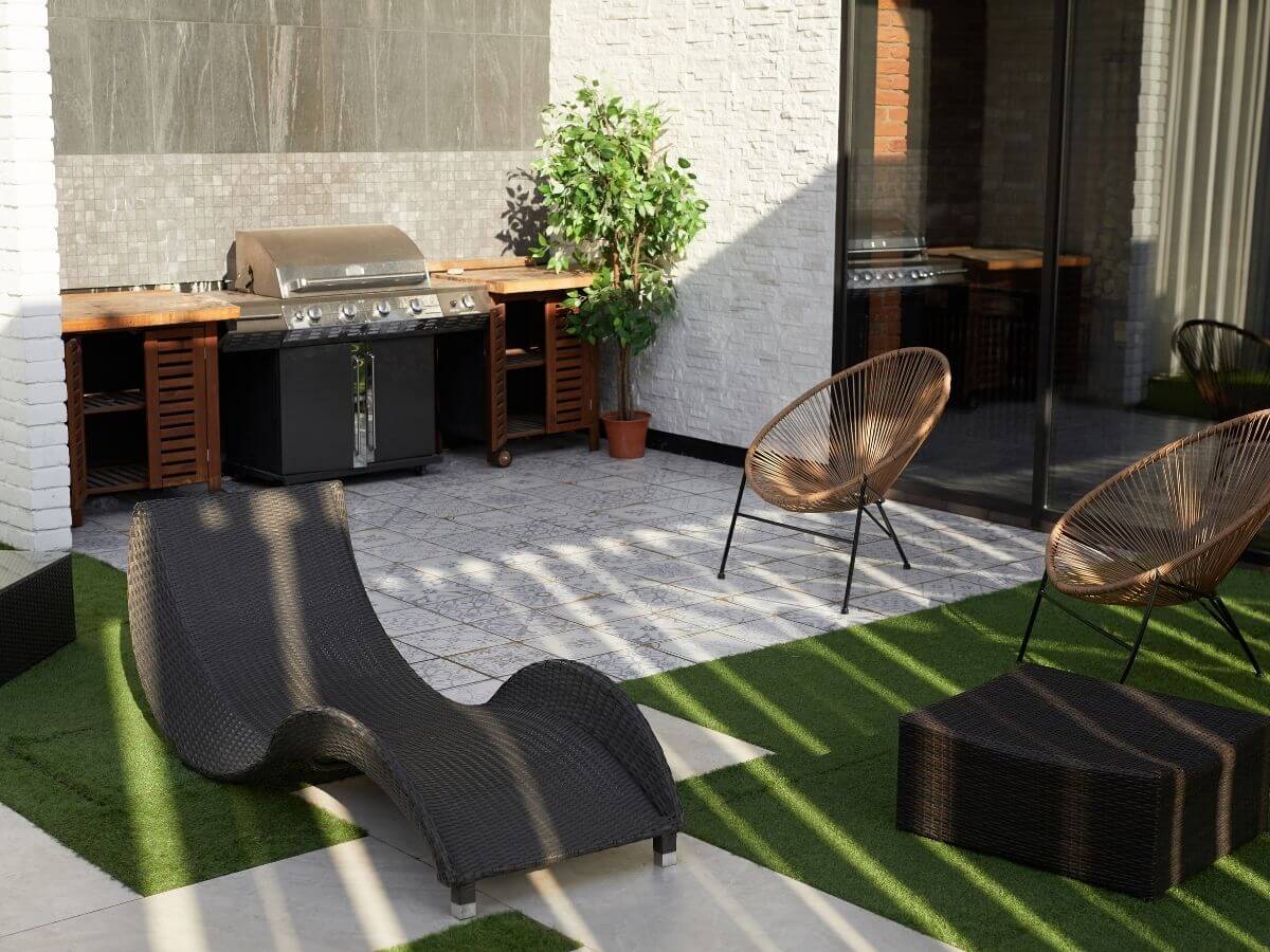 Arredo giardino con poltroncine in vimini e lettino in vimini e barbecue