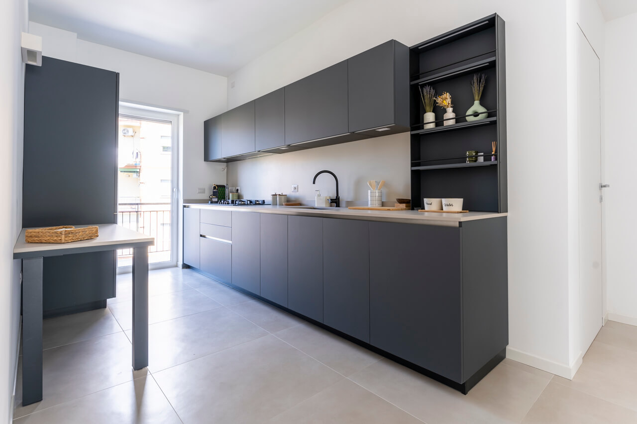 cucina a vista in nero in contrasto con il pavimento chiaro